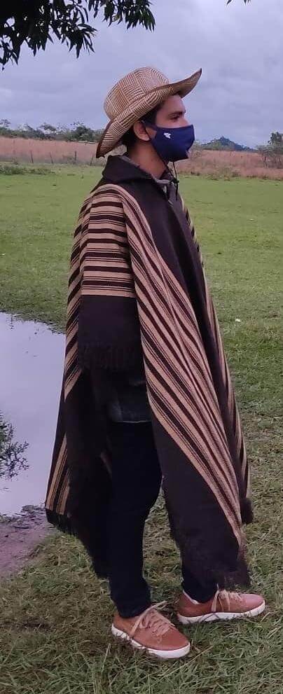 Artesão vestindo poncho e chapéu de palha da produção Guarani em área rural